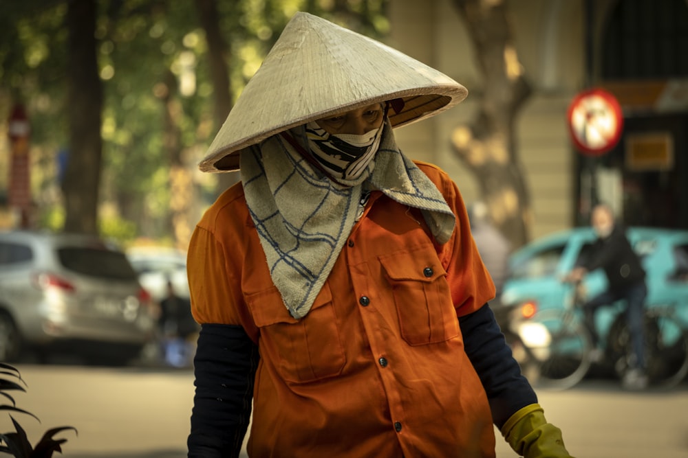 a man in an orange shirt and hat walking down a street