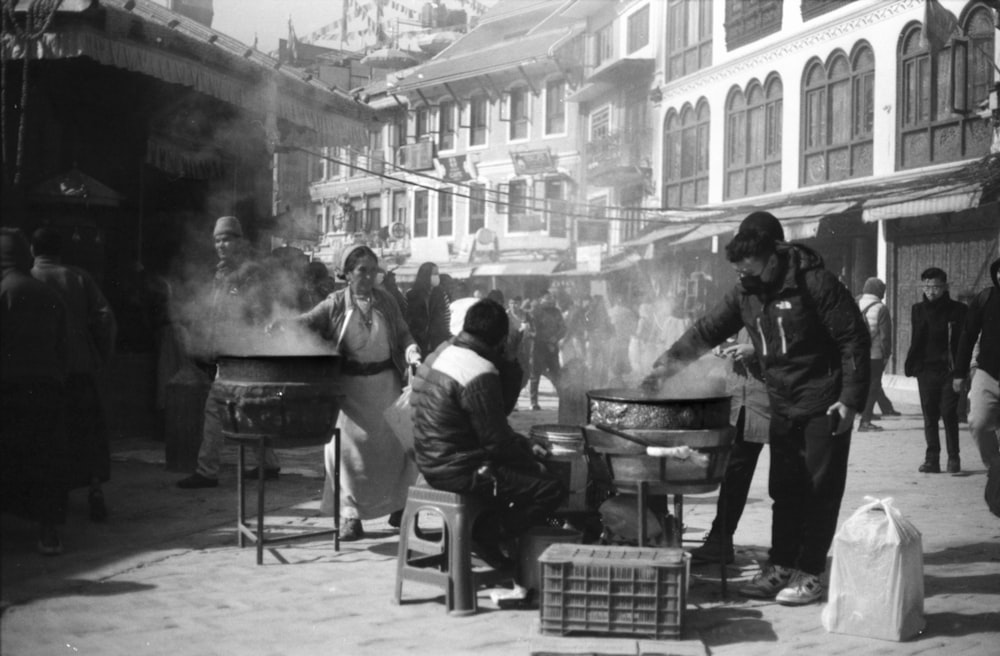 a group of people standing around a bbq on a street