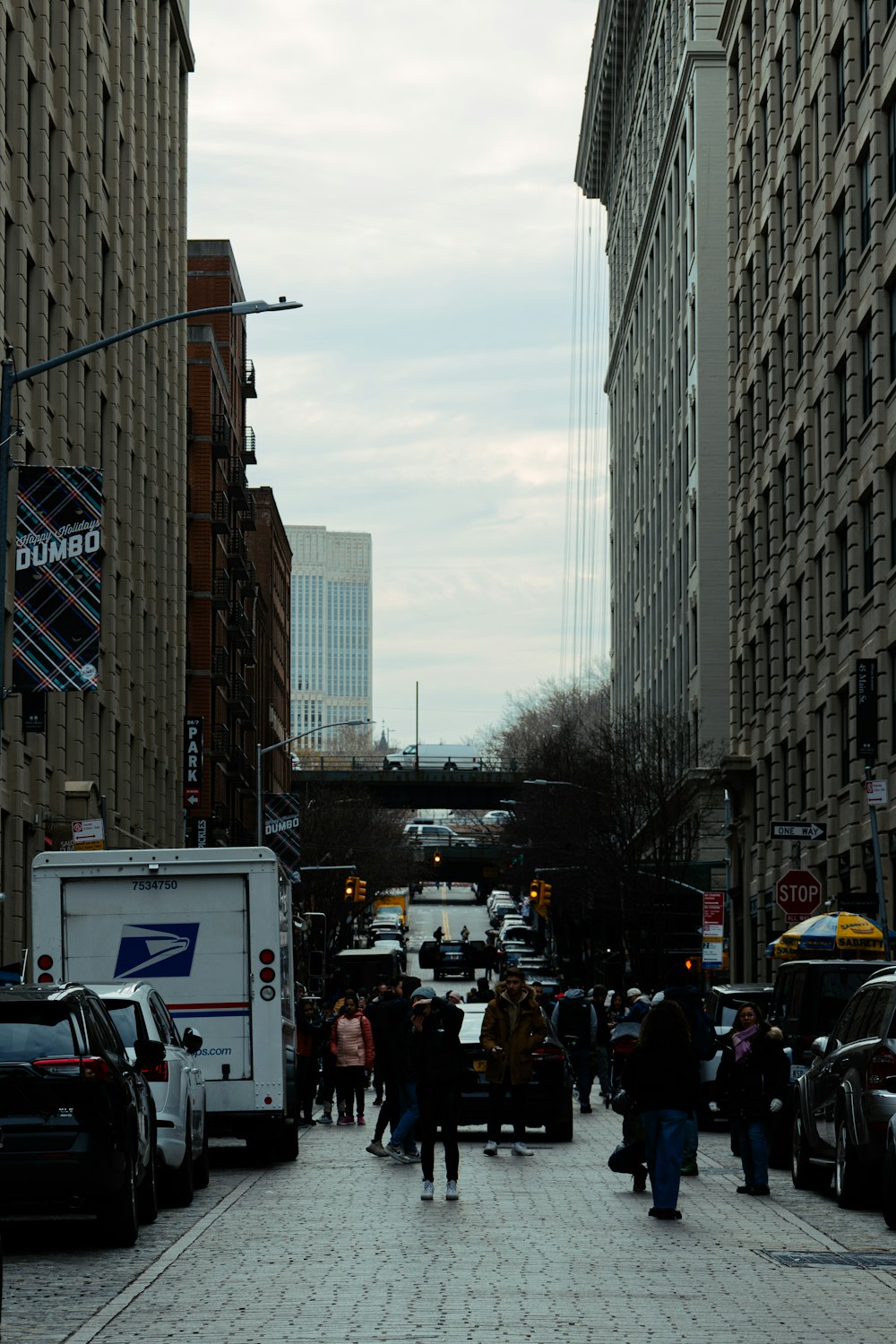 a group of people walking down a street next to tall buildings