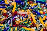 A colorful assortment of keychains featuring small sneaker and basketball designs, with various branding labels. The items are densely packed, displaying a mix of shapes and vibrant colors such as yellow, green, blue, red, and black.