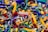 A colorful assortment of keychains featuring small sneaker and basketball designs, with various branding labels. The items are densely packed, displaying a mix of shapes and vibrant colors such as yellow, green, blue, red, and black.