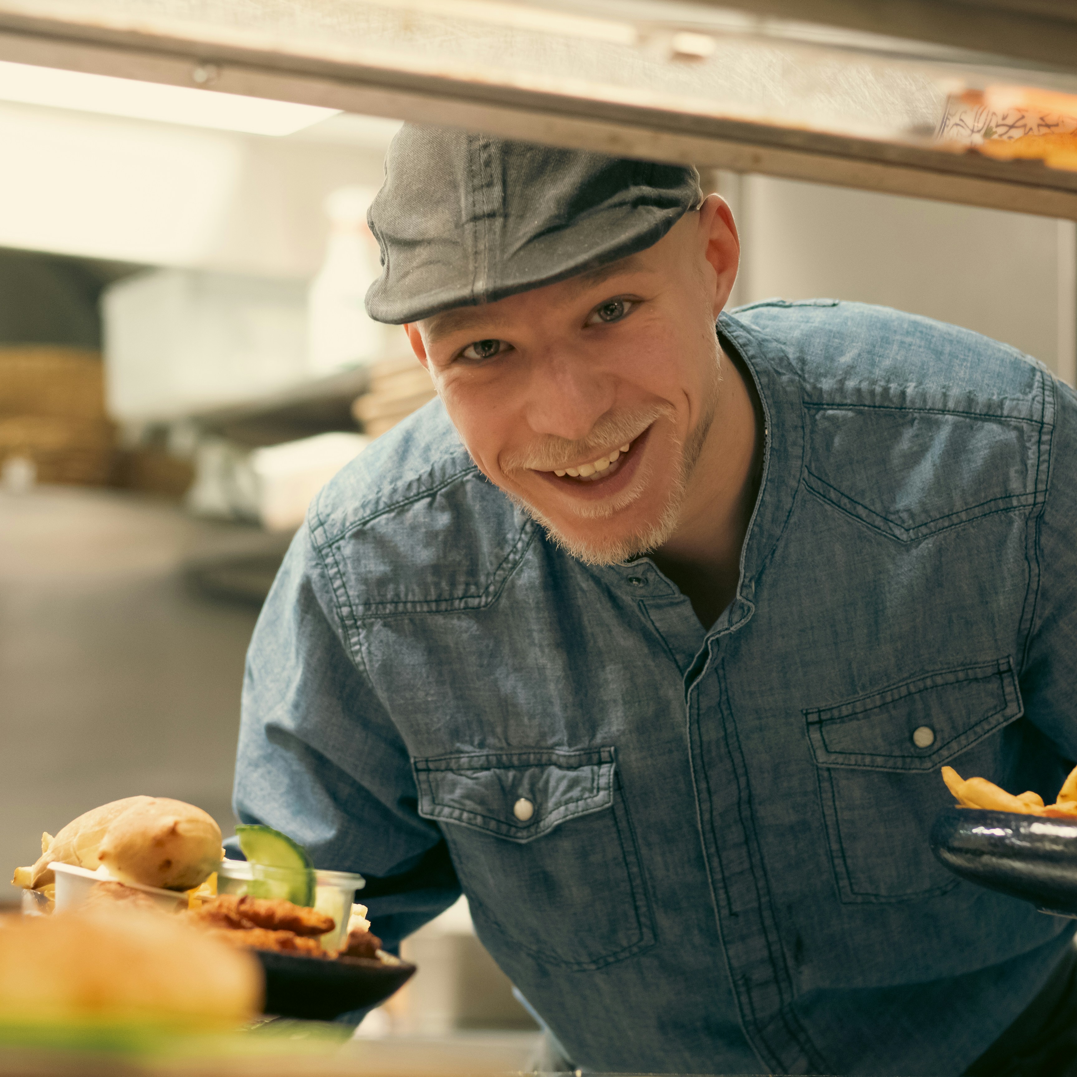 a man in a blue shirt and hat smiling at a plate of food