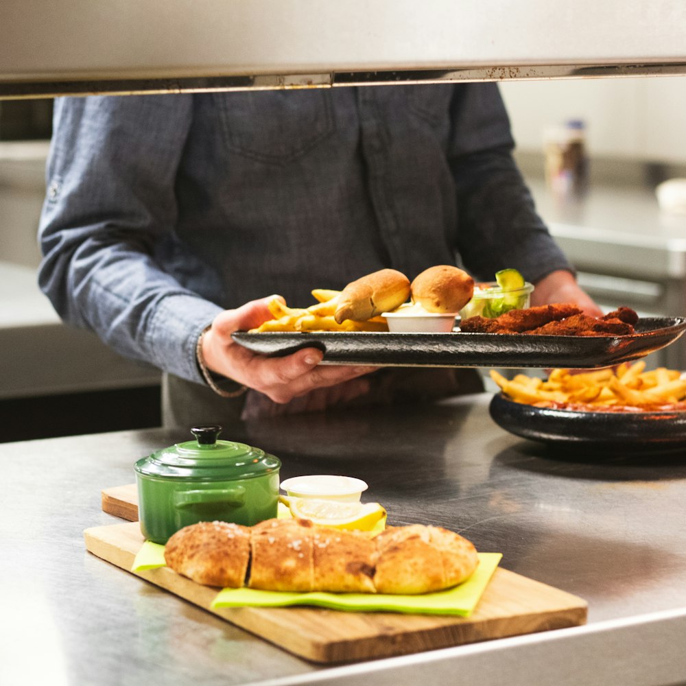 a person holding a tray of food in a kitchen