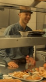 A smiling staff member serving food to happy customers.