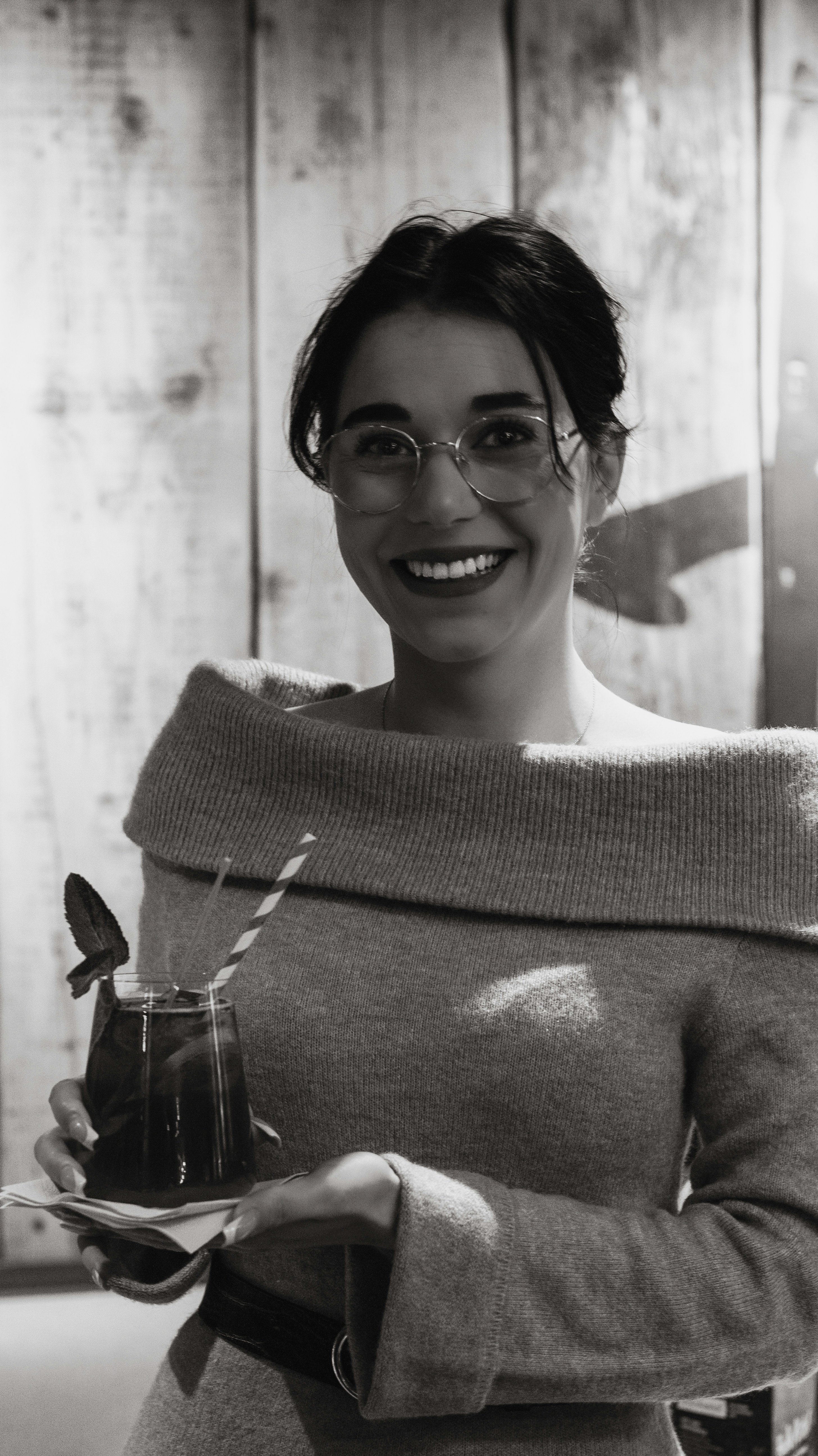 a woman in a sweater holding a drink