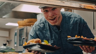 a man holding a plate of food in a kitchen