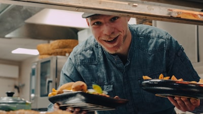 a man holding a plate of food in a kitchen