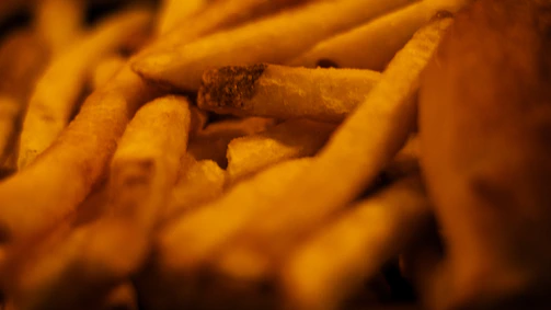 Detailed image of premium frozen french fries being inspected for quality on a sleek conveyor belt.