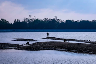 a man standing on a beach next to a body of water