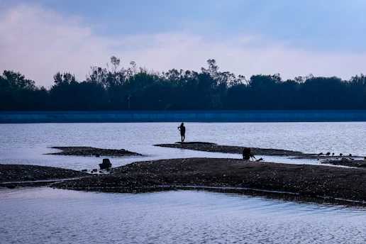 a man standing on a beach next to a body of water