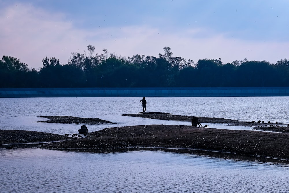 a man standing on a beach next to a body of water