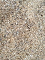 Close-up of coarse sand grains spilling from a heavy equipment loader bucket.