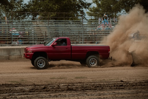 a red truck driving down a dirt road