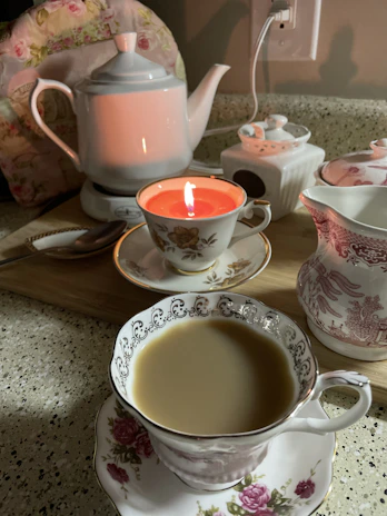 A cozy tea setup with a teacup, herbal leaves, and a small honey jar.