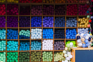 Close-up of colorful yarn balls arranged neatly on wooden shelves.