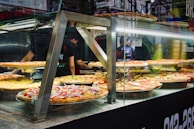 Artisan pizzas with fresh toppings displayed inside the transparent window of the vending machine.