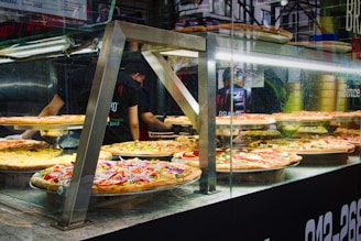 A takeout counter displaying a variety of freshly made pizzas ready for customers.