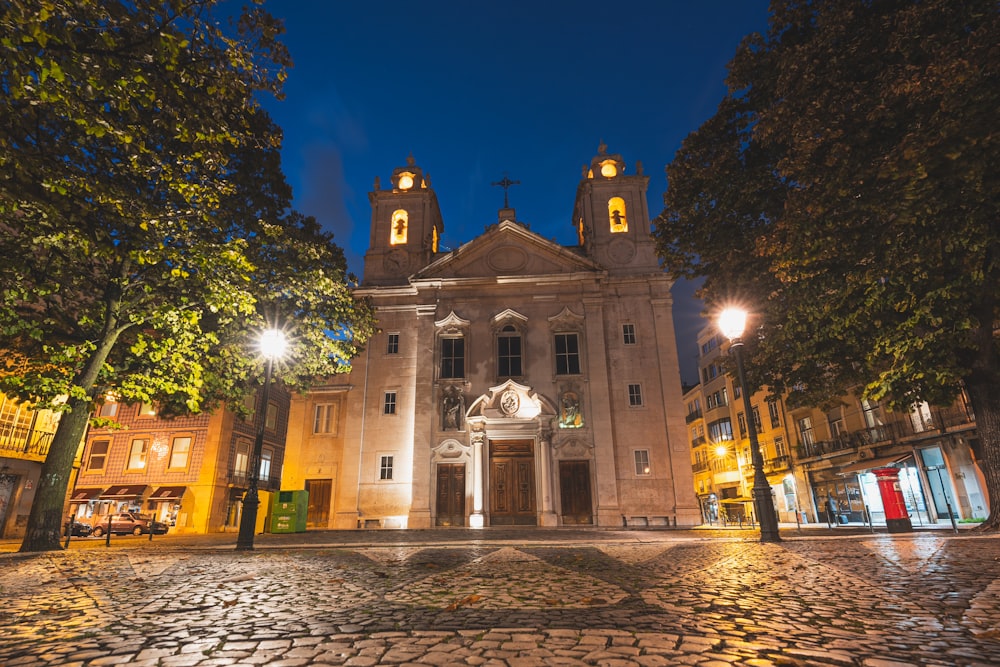 a church lit up at night on a cobblestone street