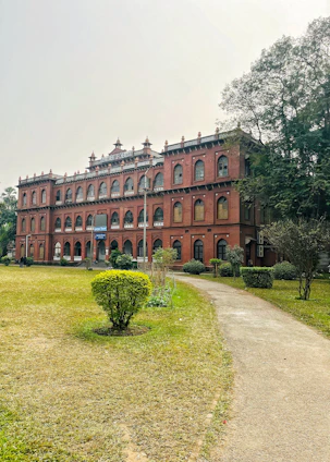 Front view of Charbhuja Chemist College building with students engaged in practical training outside.
