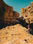 A rugged backpack resting on sunlit desert rocks under a clear sky.