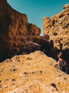 A rugged backpack resting on sunlit desert rocks under a clear sky.