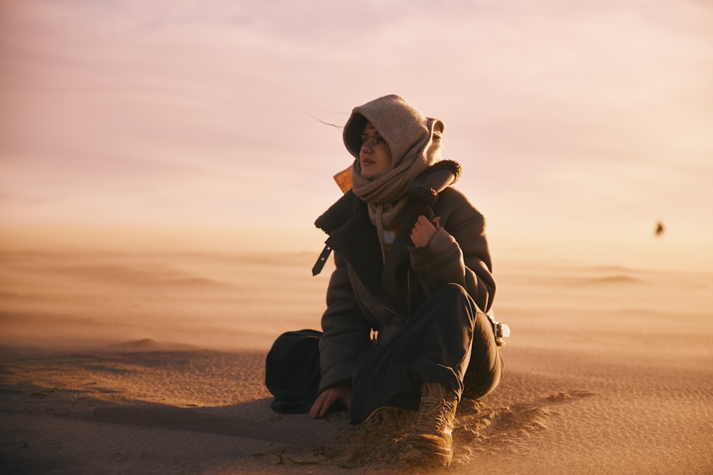 une personne assise dans le sable avec un chapeau