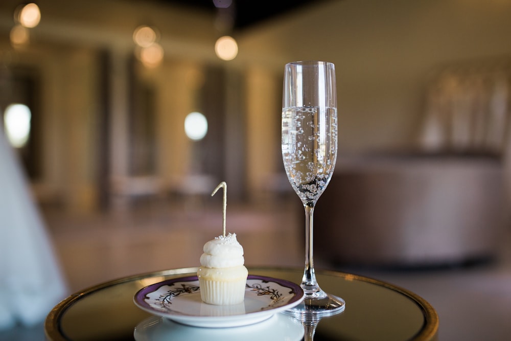 a glass of champagne and a cupcake on a table