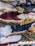 A close-up view of a colorful, textured woven textile with a variety of yarns and fibers intricately woven together. The pattern features stripes and abstract shapes with different weaving techniques, creating a dynamic and intricate surface.