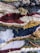 A close-up view of a colorful, textured woven textile with a variety of yarns and fibers intricately woven together. The pattern features stripes and abstract shapes with different weaving techniques, creating a dynamic and intricate surface.