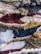 A close-up view of a colorful, textured woven textile with a variety of yarns and fibers intricately woven together. The pattern features stripes and abstract shapes with different weaving techniques, creating a dynamic and intricate surface.