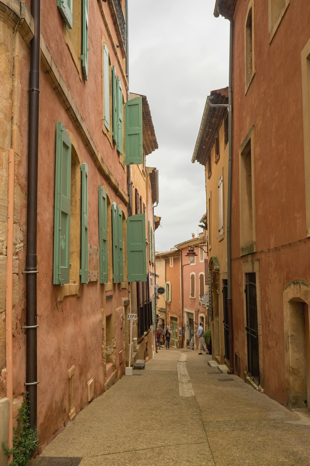 a narrow street with green shutters on the windows