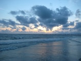 Soft clouds above a calm ocean horizon during sunrise.
