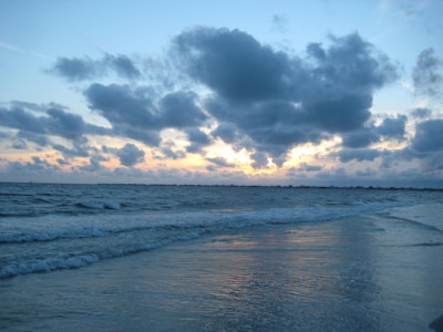 Soft clouds above a calm ocean horizon during sunrise.
