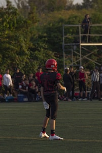 A young boy practicing football on a grassy field.