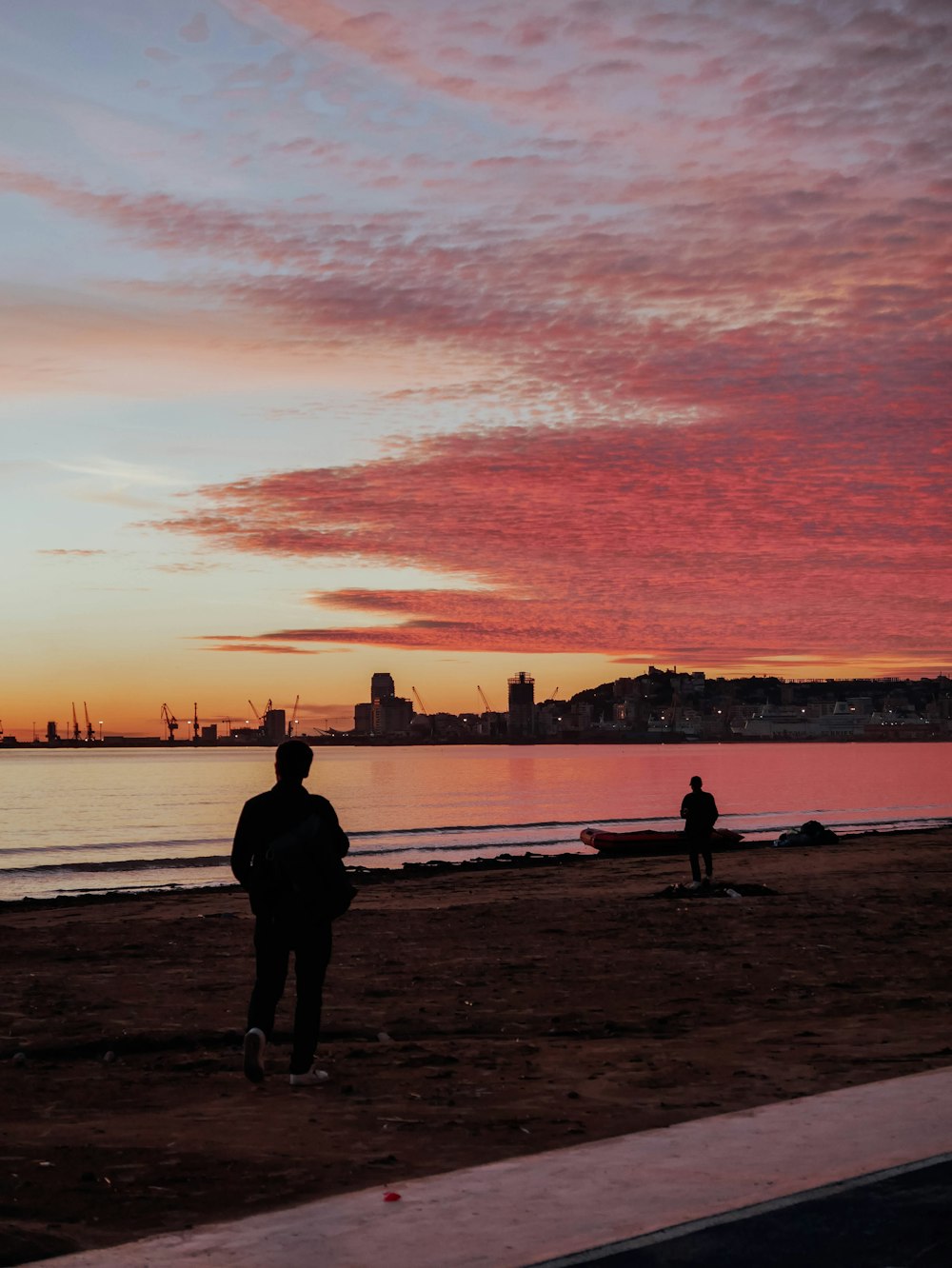 a couple of people standing on top of a sandy beach