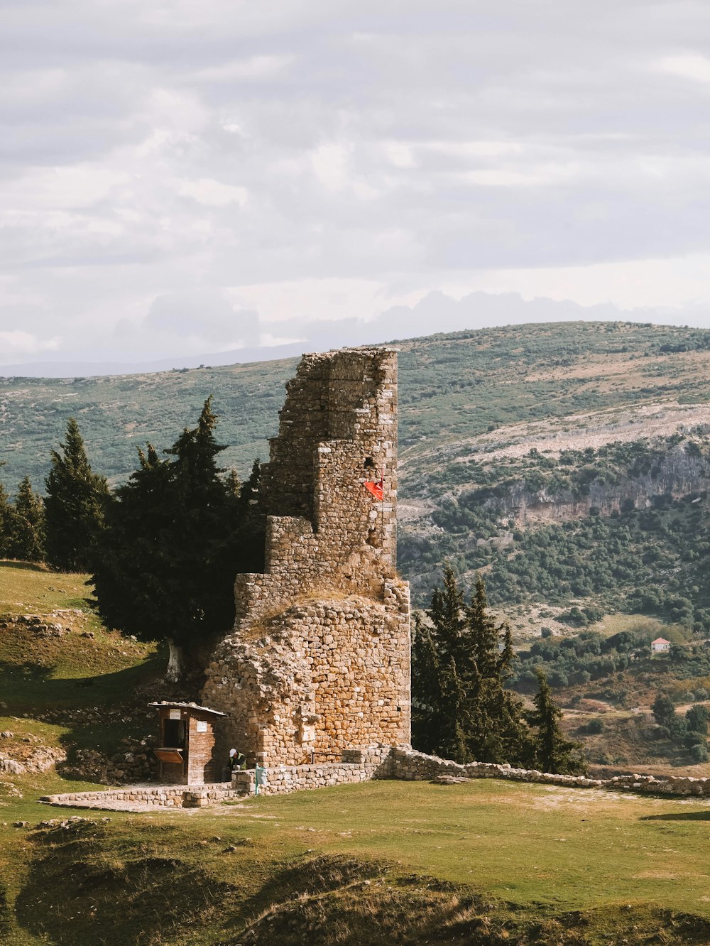 una torre di pietra che si trova in cima a una collina verde lussureggiante