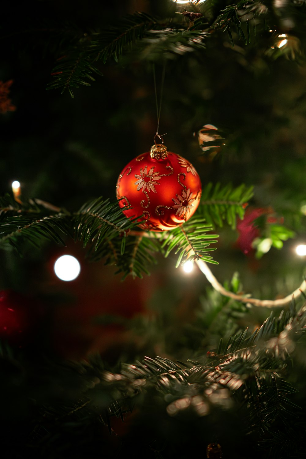 a red ornament hanging from a christmas tree