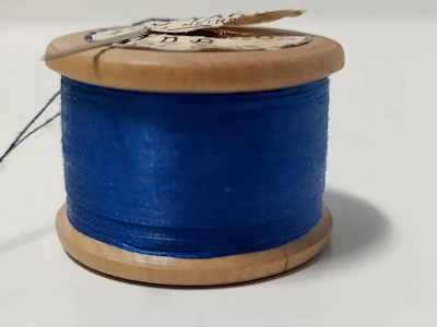 Close-up of a bright, colorful PLA filament spool casting soft shadows on a wooden table.