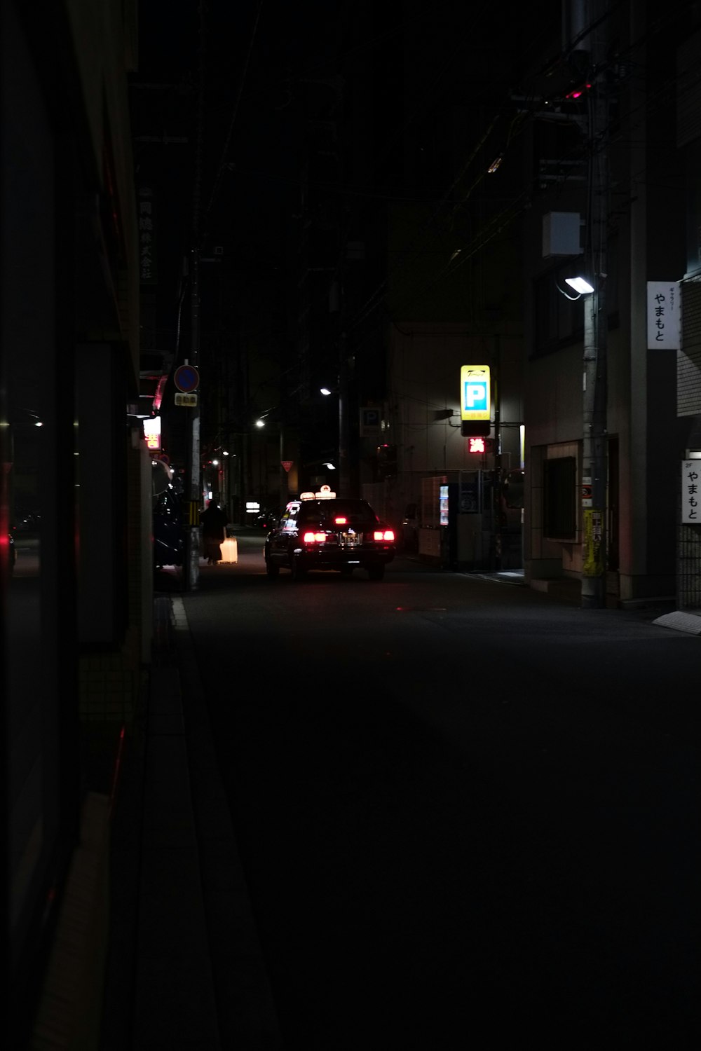 une rue de la ville la nuit avec des voitures garées sur le bord de la route