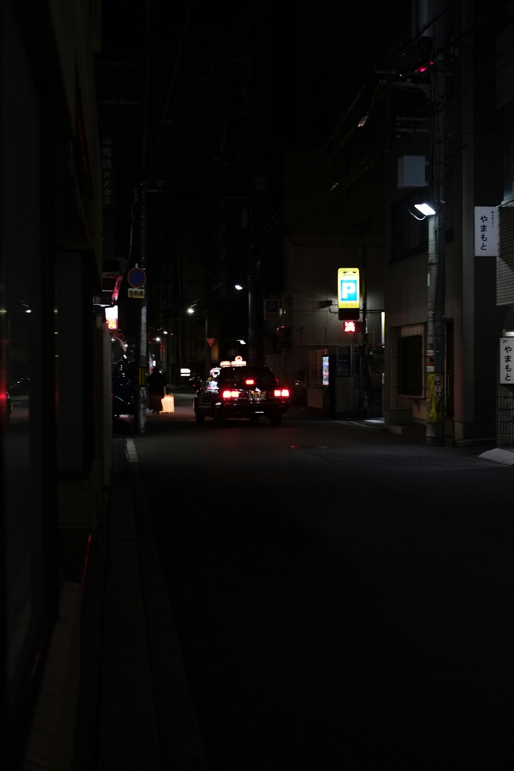 a city street at night with cars parked on the side of the road