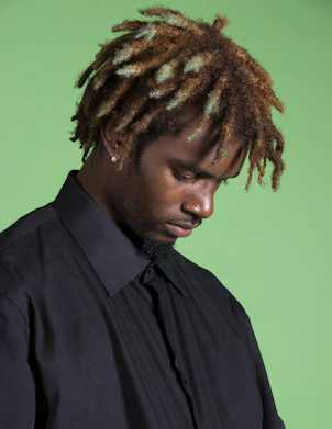 a man with dreadlocks looking down at his cell phone