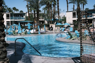 Guests enjoying a relaxing swim in the resort's clear blue pool surrounded by lounge chairs.