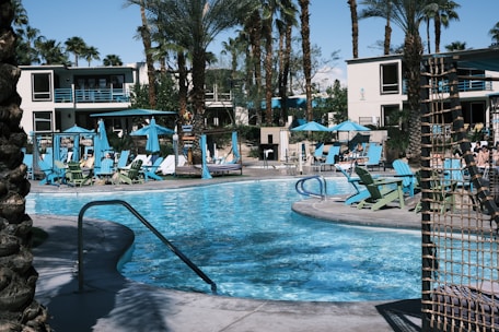 Guests enjoying a relaxing swim in the resort's clear blue pool surrounded by lounge chairs.