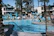 A smiling guest relaxing by the sparkling swimming pool at Angelos Kandia Apartments on a sunny day.