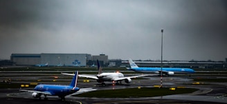 A busy airport runway with airplanes taxiing under a cloudy sky.