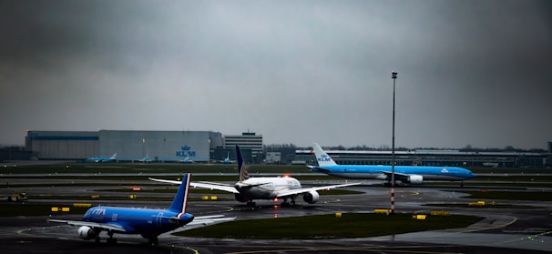 A busy airport runway with airplanes taxiing under a cloudy sky.