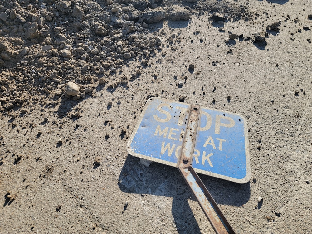 a blue sign sitting on top of a dirt field