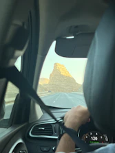 A car driving on a highway with a driver visible through the window.