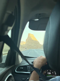 A car driving on a highway with a driver visible through the window.