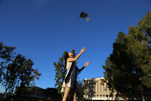 A proud graduate tossing their cap in the air on a sunny campus lawn.